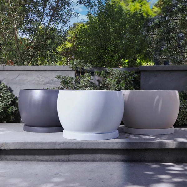 Corsica ModaCAST lightweight fiberglass planters in three colors on a concrete step in a garden
