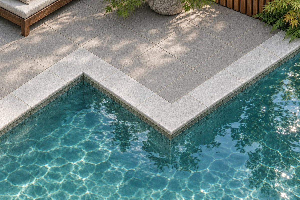 ModaPAVE concrete pool coping in Platinum around a pool with inside and outside corners, beside a square paver deck
